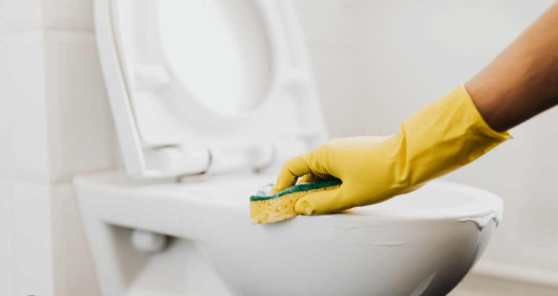 Cleaner scrubbing a commercial toilet